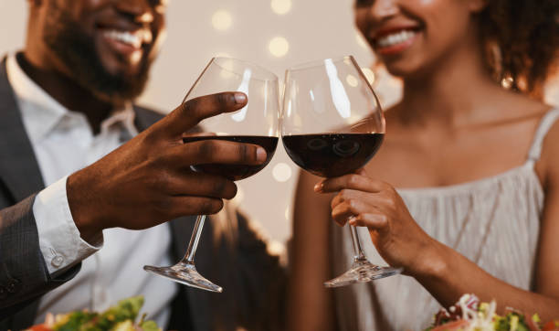Two people clinking wine glasses with a blurred background